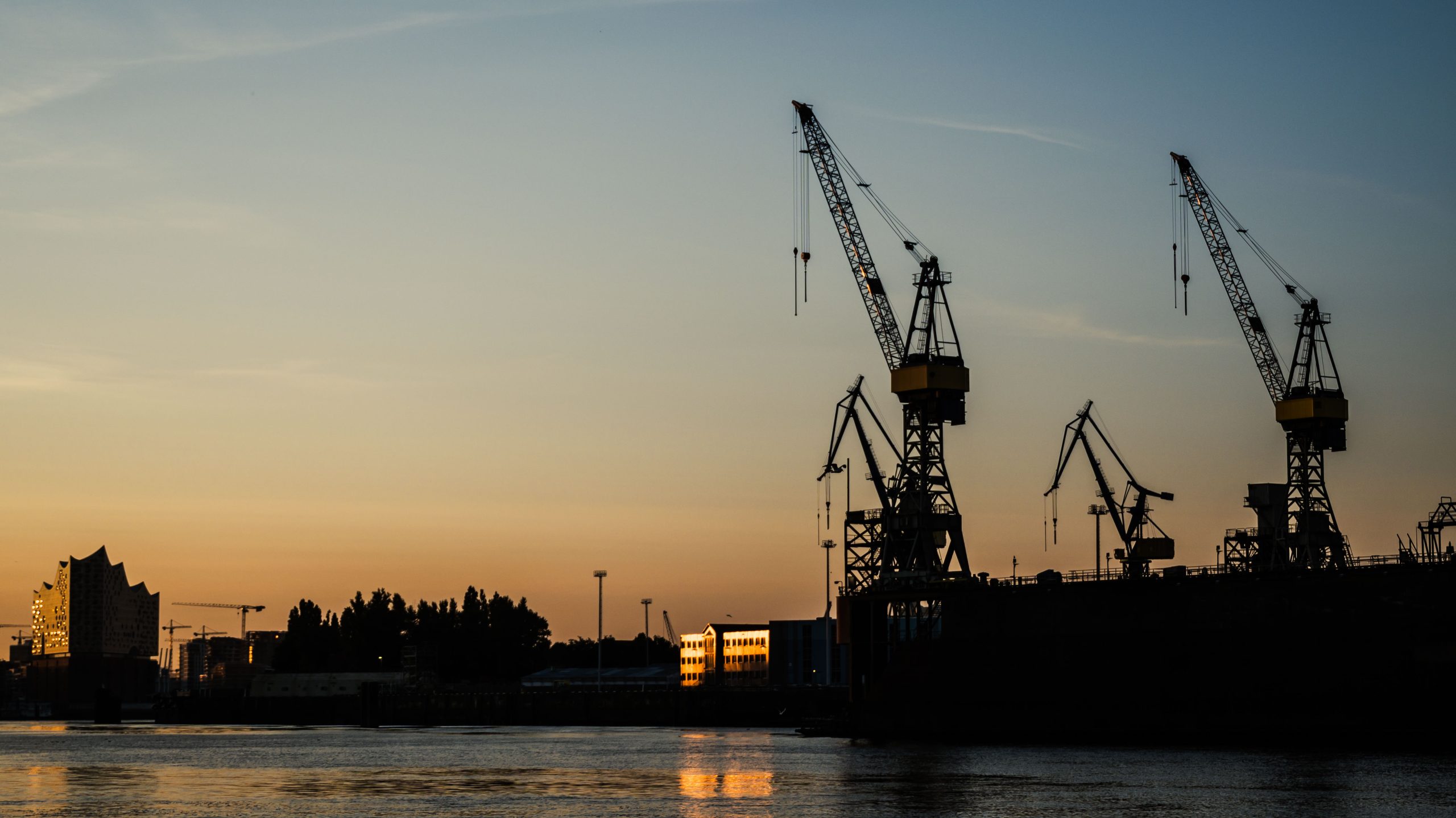 Hafenkräne als Silhouetten vor dem Morgenhimmel in Hamburg