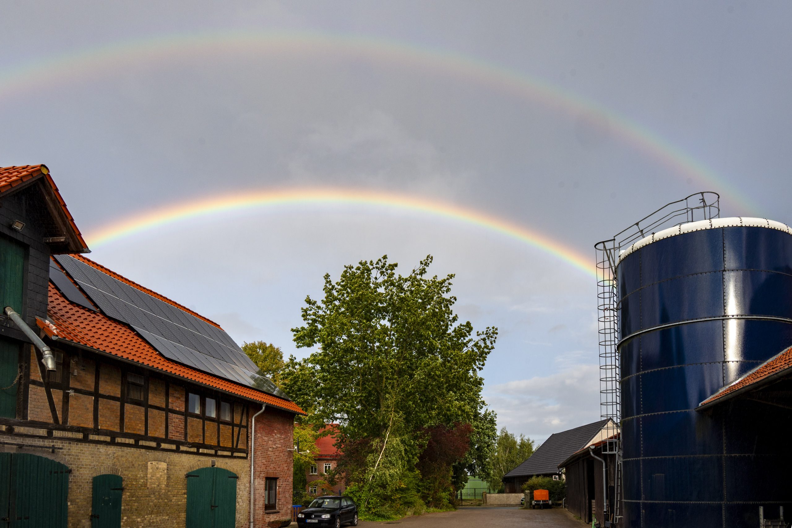 Doppelter Regenbogen über Gebäuden und einem Baum in der Region Hannover
